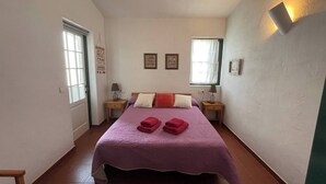 A bedroom with a bed, two bedside tables, a window, and a door.