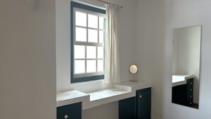 Ein Badezimmer mit Fenster, Spiegel und Waschbecken.