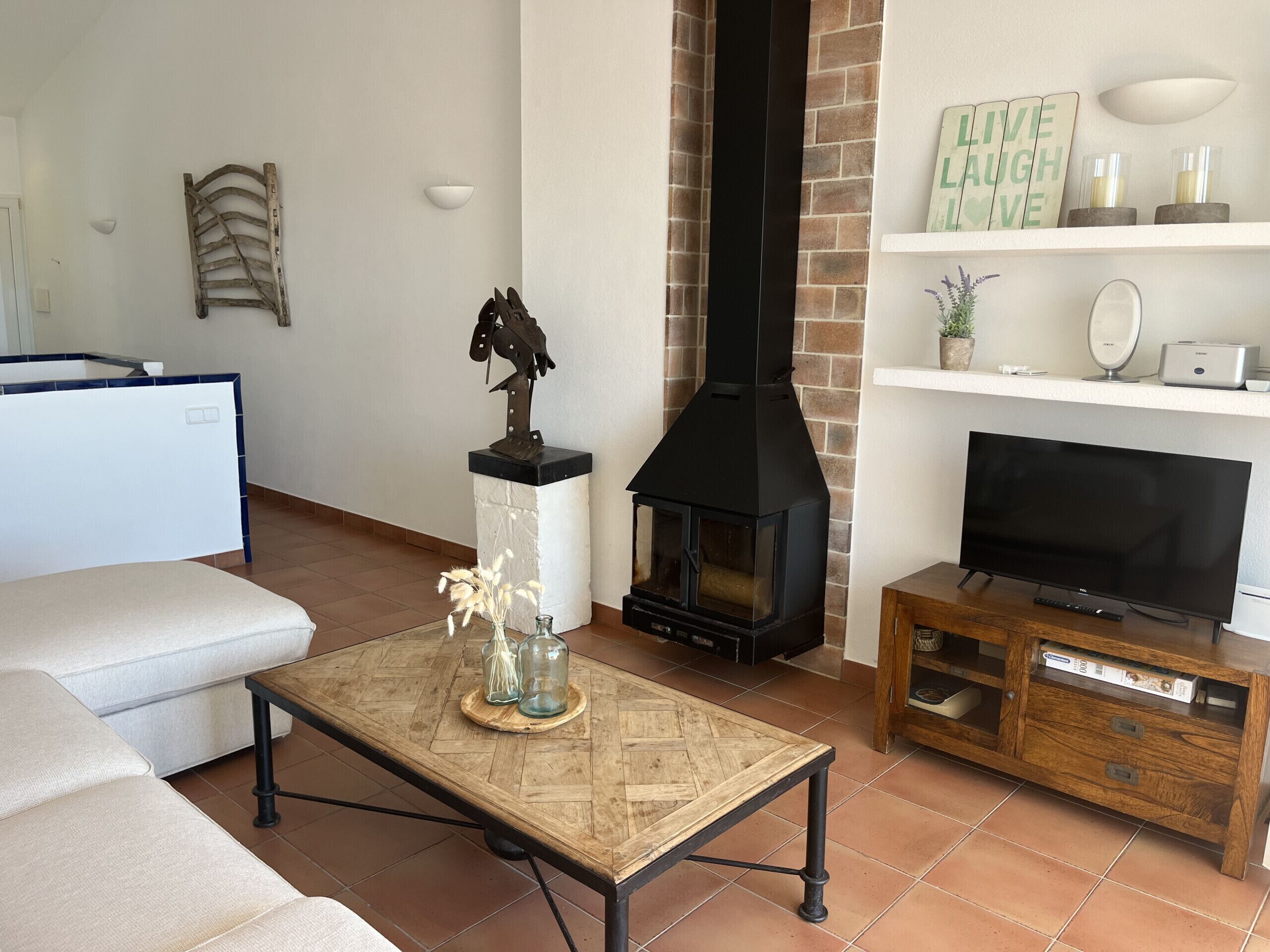 Un soggiorno con camino, televisione, divano e tavolino da caffè con oggetti decorativi.