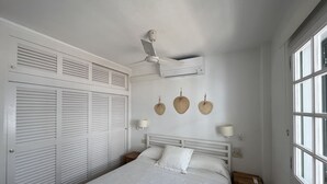 Et soveværelse med seng, ventilator, klimaanlæg og et vindue.