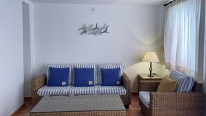 Una sala de estar con un sofá a rayas, una mesa de centro de mimbre y una lámpara.