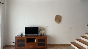 Un salón con mueble de madera para entretenimiento, televisor de pantalla plana y un adorno colgante en la pared.