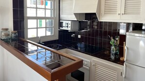 Eine Küche mit schwarzem Fliesenrückwand, weißen Schränken, einer eingebauten Mikrowelle und einem Kühlschrank.
