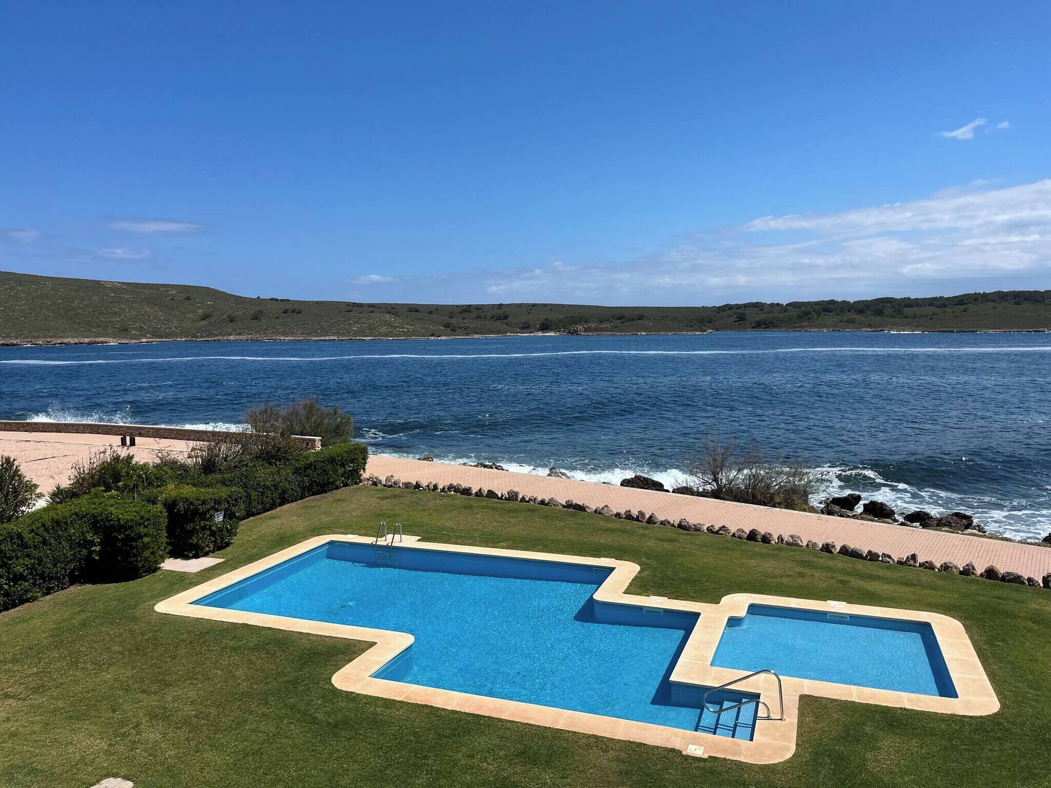 A swimming pool with a view of the sea and hills.