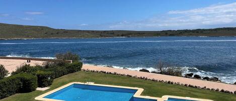 A swimming pool with a view of the sea and hills.