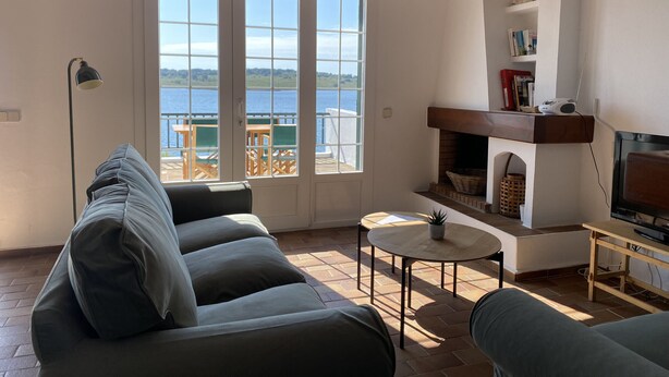 Una sala de estar con sofá, una mesita, chimenea y vistas al exterior.