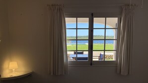 Una habitación con cama, lámpara y ventana con cortinas.