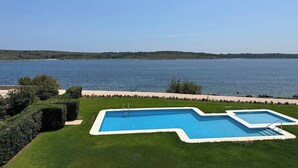 A swimming pool with a view of a lake and hills in the background. - Apartment with sea views and pool in Fornells (Fornells)