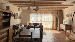 A cozy living room with a wooden ceiling, a dining table, and a sofa.