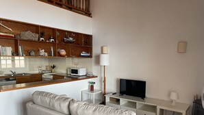Een moderne keuken met houten kasten, een magnetron en een tv op een standaard.
