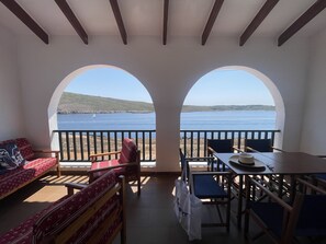 A balcony with a view of the sea, wooden furniture, and a table. - First line of sea in Fornells (Fornells)