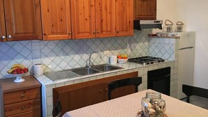 Une cuisine avec des meubles de rangement en bois, un évier, une cuisinière et une table agrémentée d’un vase décoratif.
