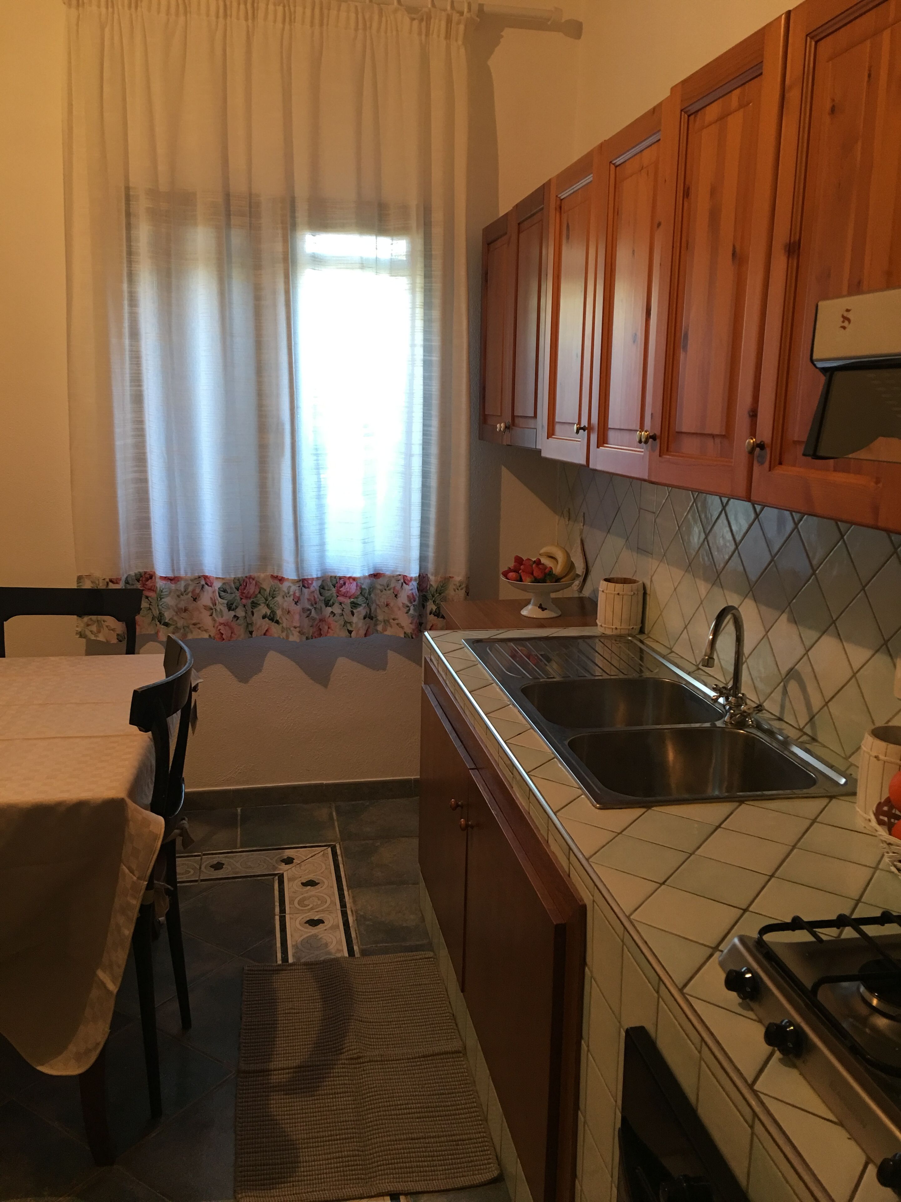 A kitchen with wooden cabinets, a stainless steel sink, and a tiled backsplash.