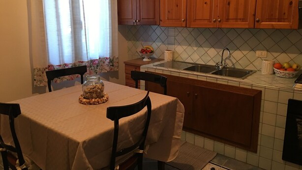 Une cuisine avec des meubles de rangement en bois, un pare-feu en carrelage, un évier et une table avec des chaises.