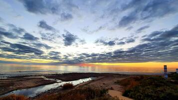 A beach with a path leading to the water, a rocky area, and a cloudy sky.