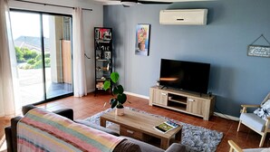 Een woonkamer met een bank, een salontafel, een televisie, een boekenkast en een plant.