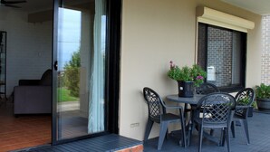 Een balkon met een schuifdeur, een tafel met stoelen en potplanten.