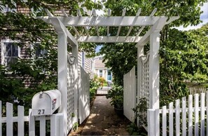 Walk through a charming covered pathway surrounded by picket fences and a mailbox.