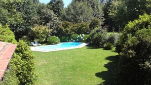 A backyard with a swimming pool surrounded by lush greenery and a brick wall. - Quinta do Arquinho, River, Pool and Nature (Ponte de Lima)