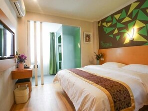 A hotel room with a bed, a bedside table with a vase of flowers, a wall with a geometric pattern, and a door leading to another room. - Vatica Hefei Lujiang Road Hotel (Hefei)