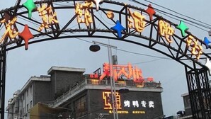 A building with a neon sign and a large archway with colorful decorations. - Vatica Hefei Lujiang Road Hotel (Hefei)