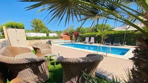 A pool area with wicker furniture and a stone wall.