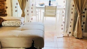 A living room with a sofa, a table with a bottle, and curtains with polka dots.