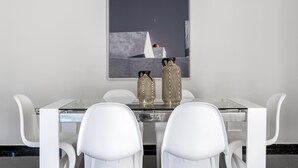 Un'area pranzo moderna con un tavolo in vetro, sedie bianche e due vasi decorati.