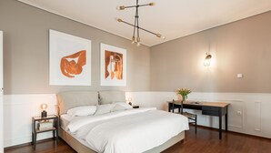Una camera da letto con un letto grande, comodini, una scrivania e due opere d'arte appese al muro.