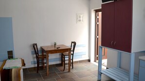 A room with a wooden table and chairs, a television mounted on the wall, and a cabinet with drawers. - Stunning 2-bed Apartment in Ios (Ios)