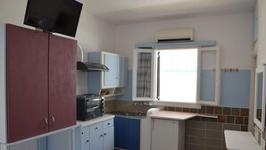 A compact kitchen with a built-in microwave, a toaster, and a sink. There is a window with curtains and an air conditioning unit above it. - Stunning 2-bed Apartment in Ios (Ios)