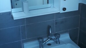 A bathroom with a white sink, a mirror above it, and a towel rack. - Stunning 2-bed Apartment in Ios (Ios)