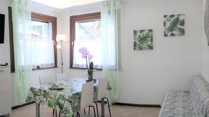 Un comedor con una mesa dispuesta para cuatro personas, sillas alrededor y un ventilador de techo.