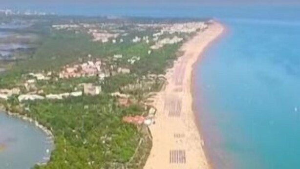 Vista aérea de una zona costera con playa y edificios cercanos.