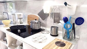 Una cocina moderna con estufa negra, encimera blanca y diversos utensilios de cocina.