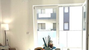 Una sala de estar minimalista con una mesa blanca preparada para dos personas, un sofá y un ventilador de techo.