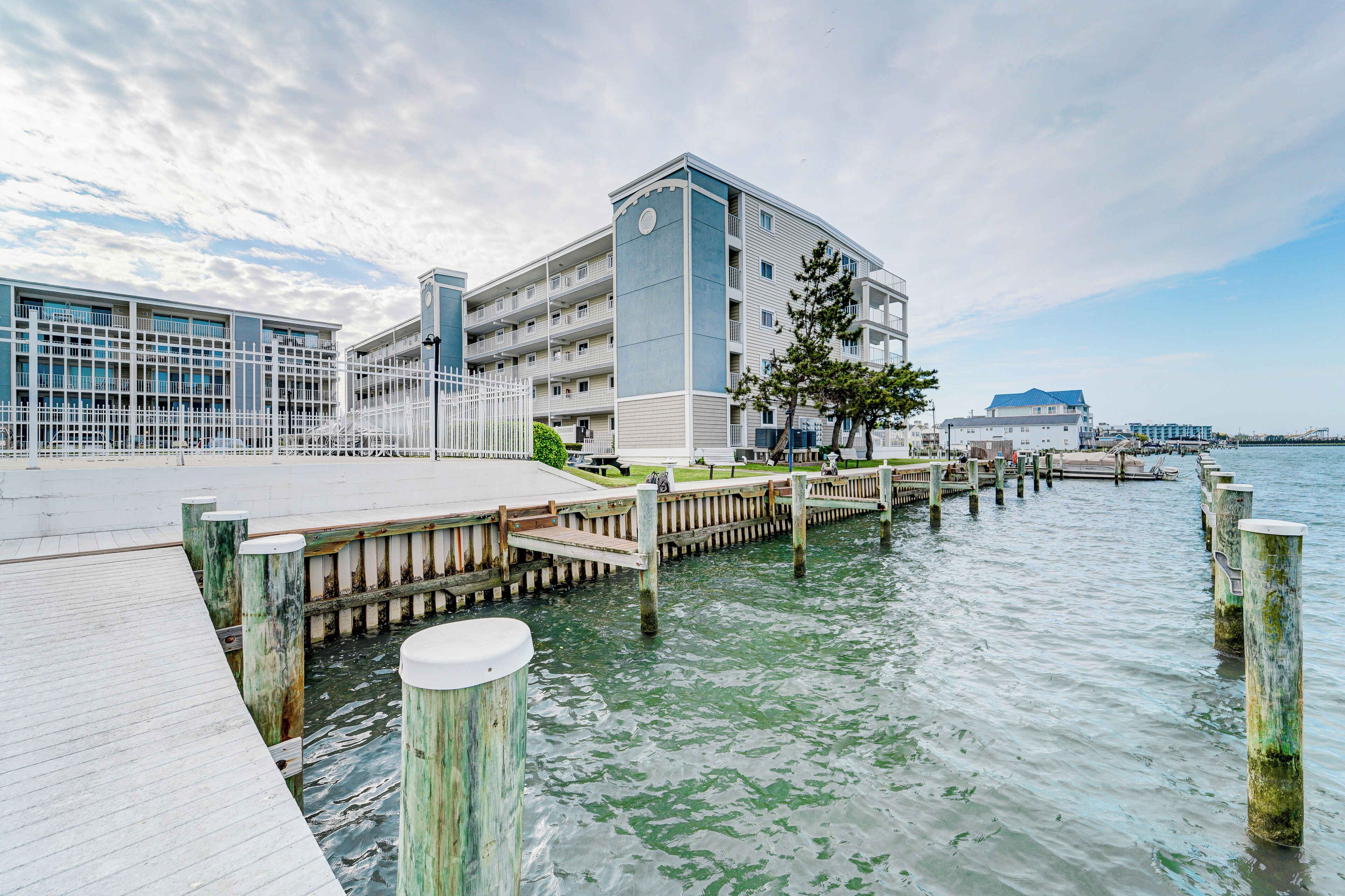 A waterfront hotel with a dock, a large building with multiple balconies, and a clear sky.