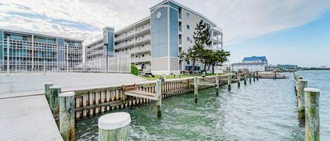 A waterfront hotel with a dock, a large building with multiple balconies, and a clear sky.