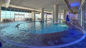 Ein Innenpool mit freiem Blick auf das Meer, großen Fenstern und einem gefliesten Boden.