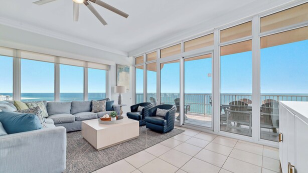 Ein geräumiger Balkon mit Meerblick, eine Sitzecke mit Sofa und Stühlen sowie ein Deckenventilator.