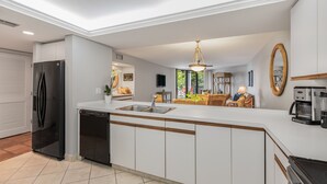 A modern kitchen with a central island, built-in appliances, and a dining area with a view. - ALMOST HEAVEN ~ Stunning 2 Bedroom, 2 Bathroom Condo with Community Pool! (Key West)