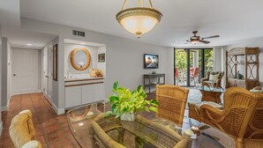 A spacious living area with wicker furniture, a glass coffee table, and a ceiling fan. - ALMOST HEAVEN ~ Stunning 2 Bedroom, 2 Bathroom Condo with Community Pool! (Key West)