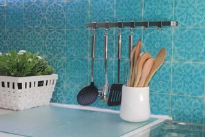 A kitchen with a hanging utensil rack, a white basket with green plants, and a white mug with wooden utensils. - Fantástica Casa com 4 Quartos na Prainha (Alvor)