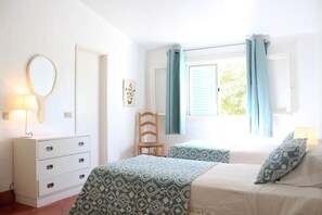 A bedroom with a bed, a chair, a dresser, a mirror, and a window with curtains. - Fantástica Casa com 4 Quartos na Prainha (Alvor)