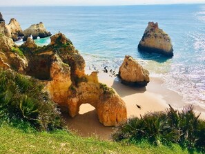 Un paisaje costero con formaciones rocosas destacadas y una playa arenosa.