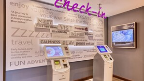 A hotel lobby with a check-in kiosk, a television screen, and motivational posters on the wall. - Premier Inn Pickering (Pickering)