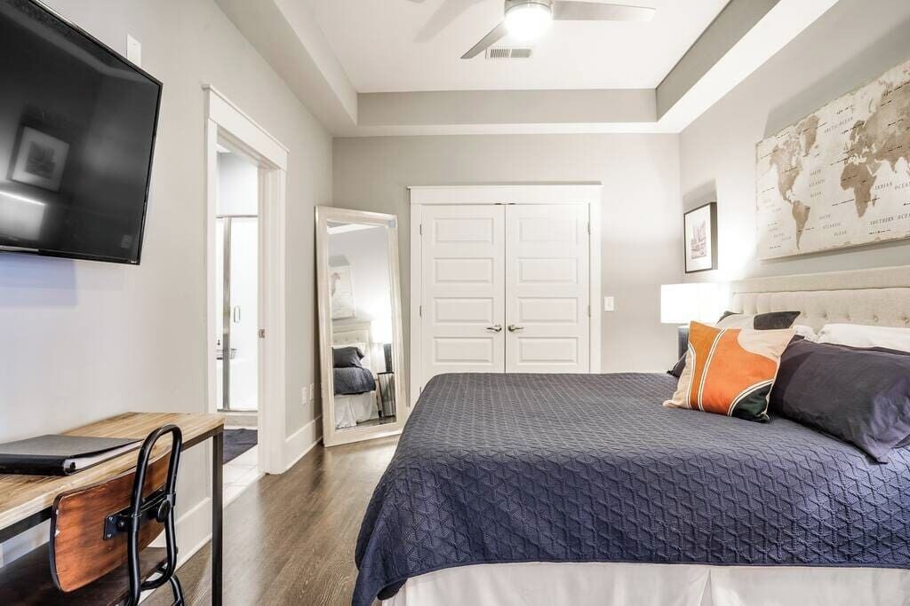 A bedroom with a bed, a desk, and a TV.