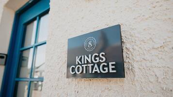 A sign for "Kings Cottage" on a textured wall.