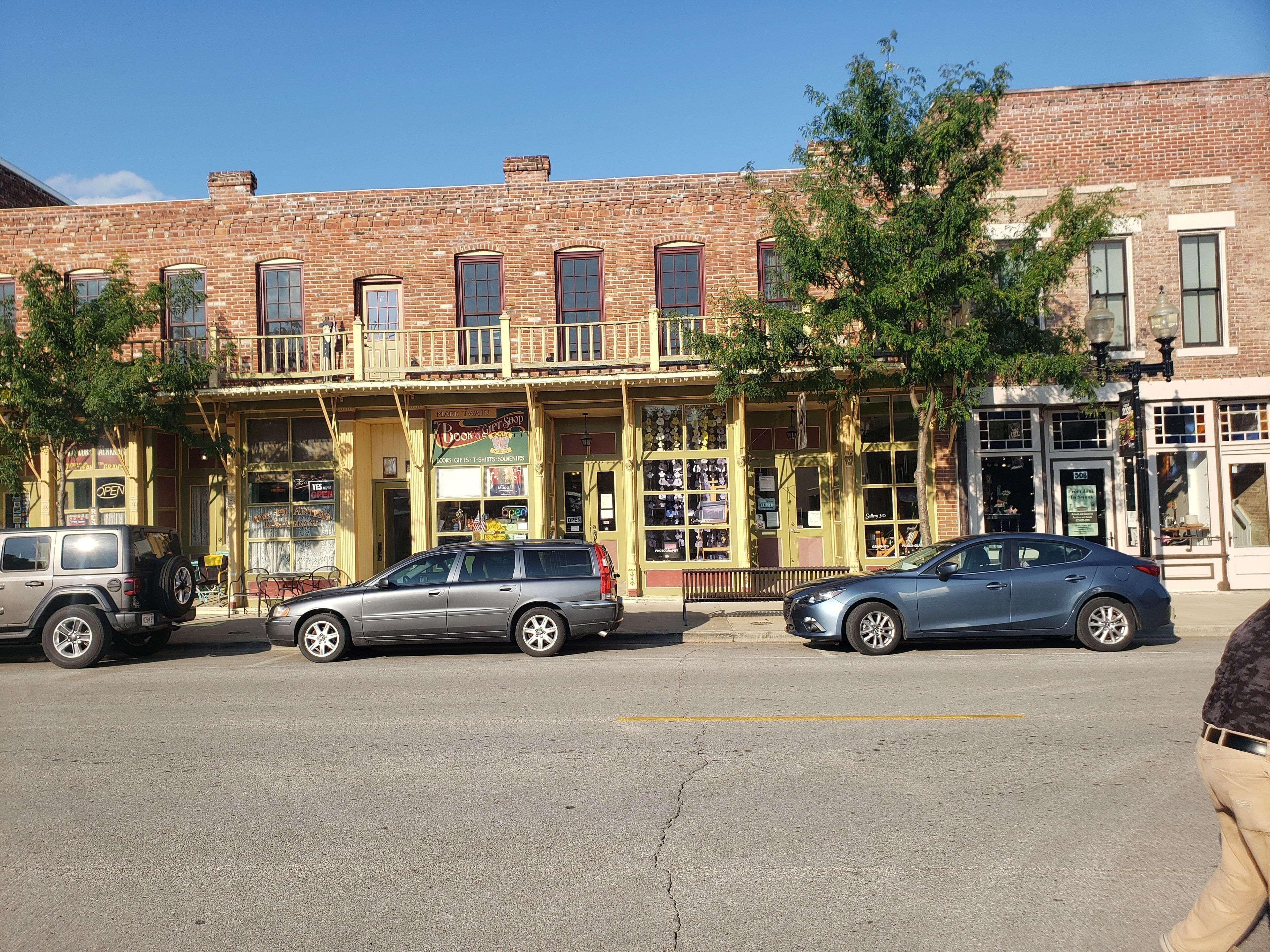 Une vue de rue avec un immeuble de deux étages, abritant une librairie au rez-de-chaussée et un restaurant à l’étage.