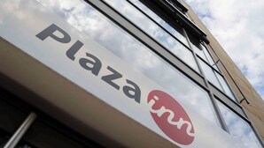 A sign with the text "Plaza inn" against a sky background.
